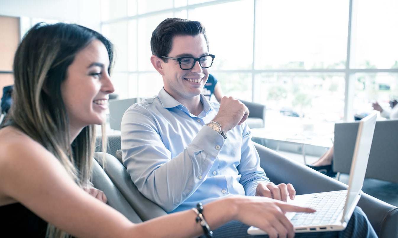 Two FAU students in front of a laptop discussing next steps after admission